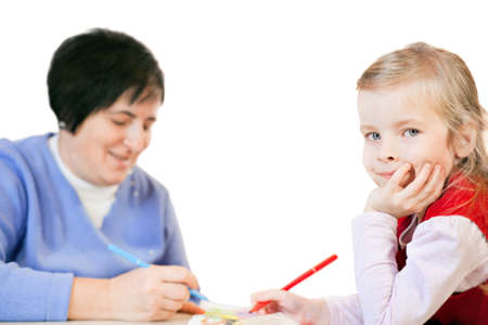 smiling little girl and happy mature woman draws in an album, isolated on white backgroundの写真素材