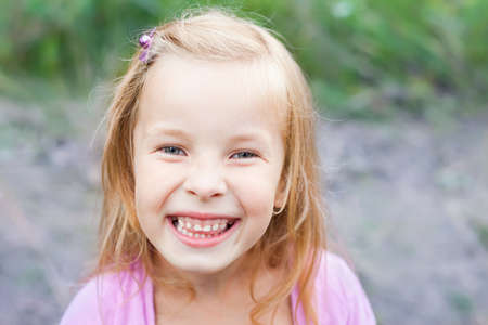 close up portrait of laughing blonde little girl outdoors in summer の写真素材