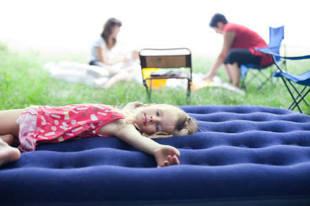 little girl lying on an inflatable mattress on picnicの写真素材