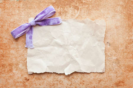 ripped piece of paper with purple bow on grunge paper background. vintage retro cardの写真素材