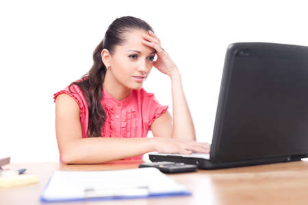 beautiful young woman sitting at office desk and working on laptop isolated on white backgroundの写真素材