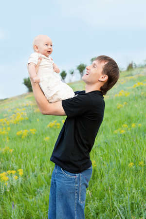 happy young man playing his baby boy on nature on slope の写真素材