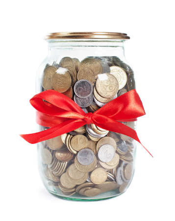Coins in the jar with red ribbon on white backgroundの写真素材