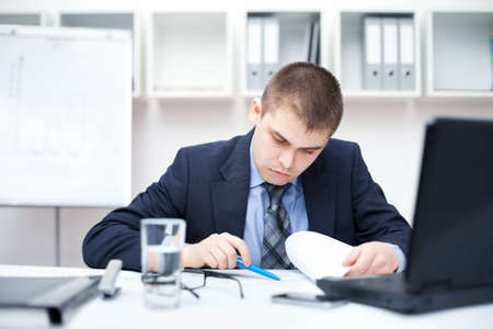 Portrait of young business man in the office doing some paperwork の写真素材