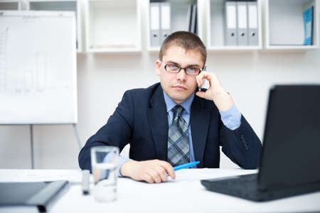 Young businessman talking on a cell phone at officeの写真素材