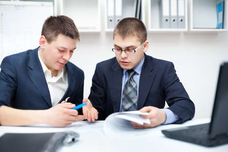 Two young businessmen working together in officeの写真素材