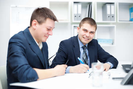 Two happy young business men working together in the officeの写真素材