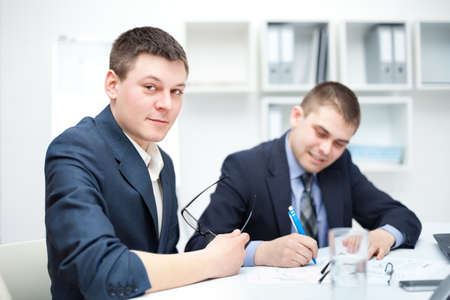 Two young businessmen signing contracts in officeの写真素材