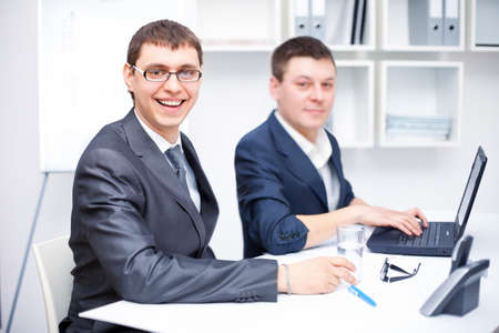 Two happy young business men working together at office の写真素材