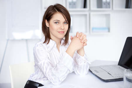 Portrait of beautiful young business woman sitting at desk at office の写真素材