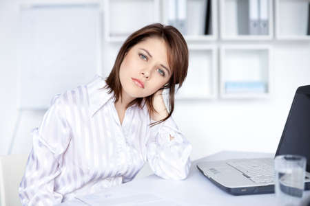 Tired young business woman in bright office の写真素材