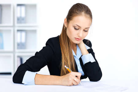Portrait of a beautiful young business woman doing some paperwork in office の写真素材
