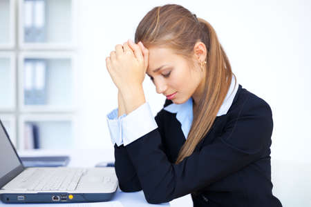 Portrait of tired young business woman with laptop computer at the officeの写真素材