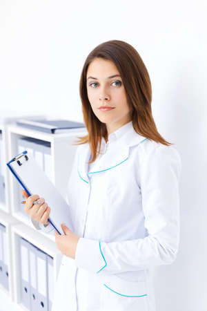 Portrait of young female doctor holding clipboard in hospitalの写真素材