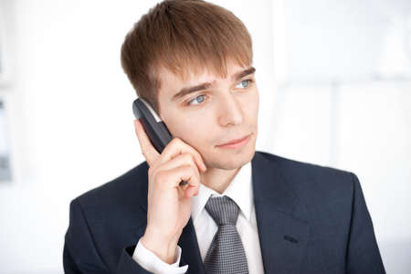 young businessman talking on cell phone in office の写真素材