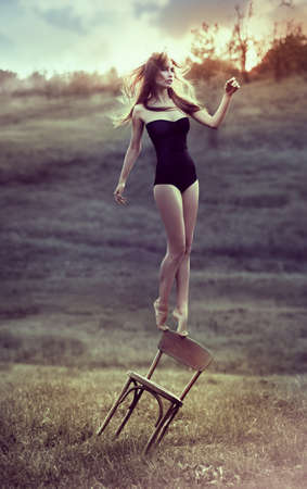 beautiful girl balances on back of chair outdoors  Artworkの写真素材