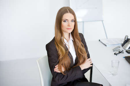 Portrait of beautiful young business woman sitting at desk at office 