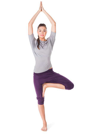 Young woman doing yoga exercise tree-pose isolated on white backgroundの写真素材