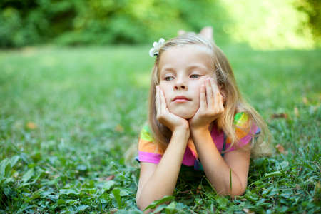 Beautiful little girl is lying on the green grassの写真素材