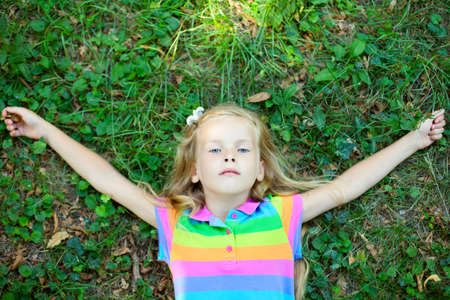 Top view of little funny girl lying on grassの写真素材