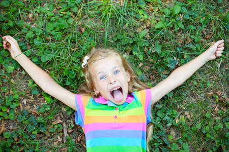 Top view of little funny girl lying on grassの写真素材