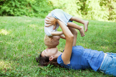 Mother and son having fun on the grass in a parkの写真素材