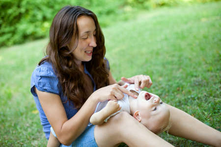 Mother and son having fun on the grass in parkの写真素材