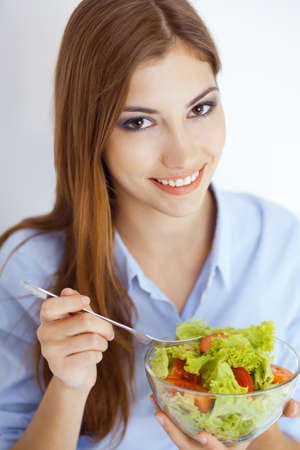 Closeup portrait of a happy young woman eating a fresh salad の写真素材