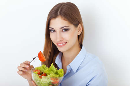 Closeup portrait of a happy young woman eating a fresh salad の写真素材