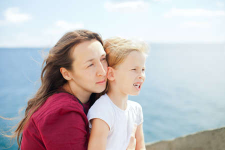 Portrait of young happy mother and daughter on sea backgroundの写真素材
