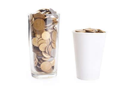 Coins in glass cup and white cup isolated on white backgroundの写真素材