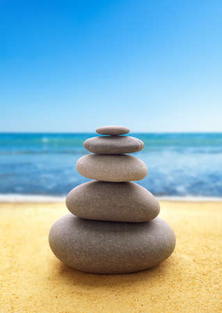 Pyramid of the stones on the sandy beach at ocean backgroundの写真素材