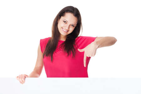 Portrait of pretty young smiling woman in red dress showing blank signboard isolated on white backgroundの写真素材