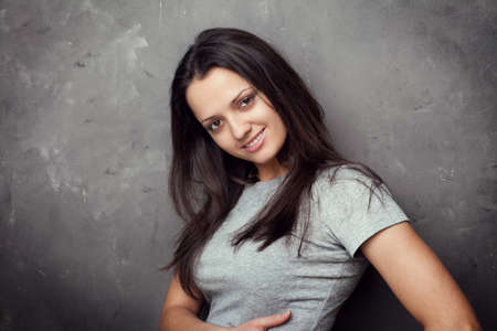 Portrait of pretty young brunette woman on textured gray backgroundの写真素材