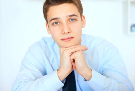Portrait of young handsome smiling businessman in bright officeの写真素材