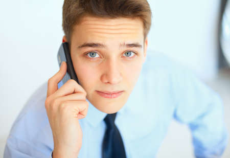 Portrait of young businessman talking on cell phone in officeの写真素材