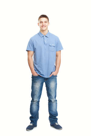 Full length portrait of smiling young man standing with hands in pockets isolated on white backgroundの写真素材