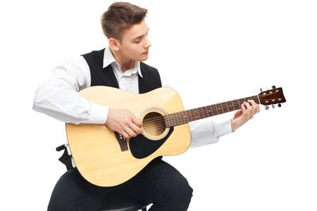 Young man playing on acoustic guitar sitting on a chair isolated on white backgroundの写真素材