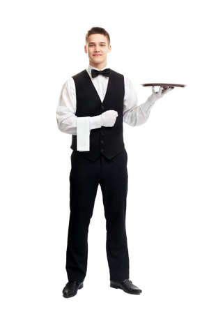 full length portrait of young happy smiling waiter with empty tray isolated on white backgroundの写真素材