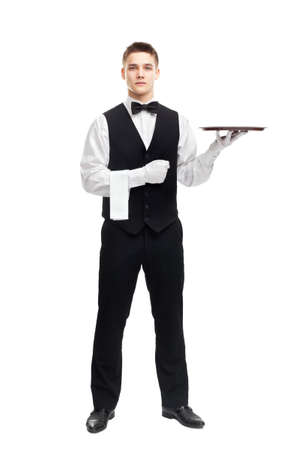 full length portrait of young happy smiling waiter with empty tray isolated on white backgroundの写真素材