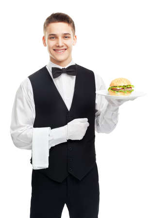 Portrait of young happy smiling waiter holding hamburger on plate isolated on white backgroundの写真素材