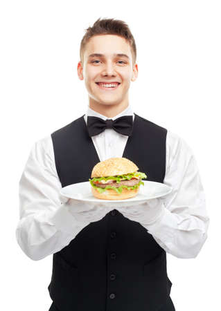 Portrait of young happy smiling waiter holding hamburger on plate isolated on white backgroundの写真素材