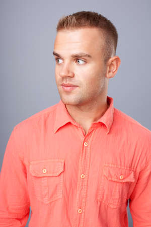 Portrait of  happy smiling young man wearing a red shirt on gray backgroundの写真素材