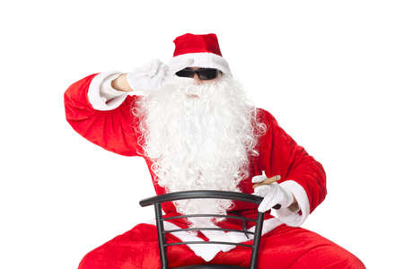 Santa Claus sitting in a chair wearing sunglasses showing dancing gesture and smoking a cigar isolated on white backgroundの写真素材