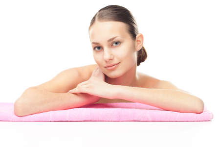 Portrait of beautiful young woman with healthy clean skin leaning on pink towel isolated on white の写真素材