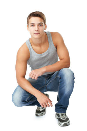 Portrait of young man squatting isolated on white backgroundの写真素材