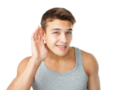 Young man with hand on ear listening carefully isolated on white backgroundの写真素材