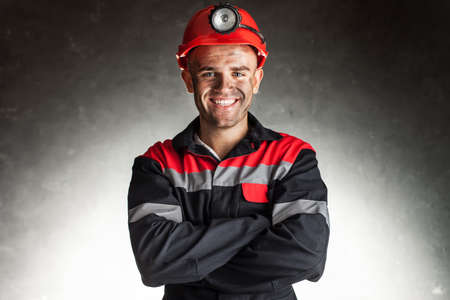 Portrait of happy smiling coal miner with his arms crossed against a dark backgroundの写真素材
