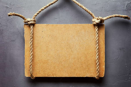 Wooden signboard with rope hanging on gray textured wallの写真素材