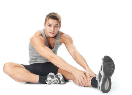 Portrait of young man athlete doing stretches exercises isolated on white backgroundの写真素材